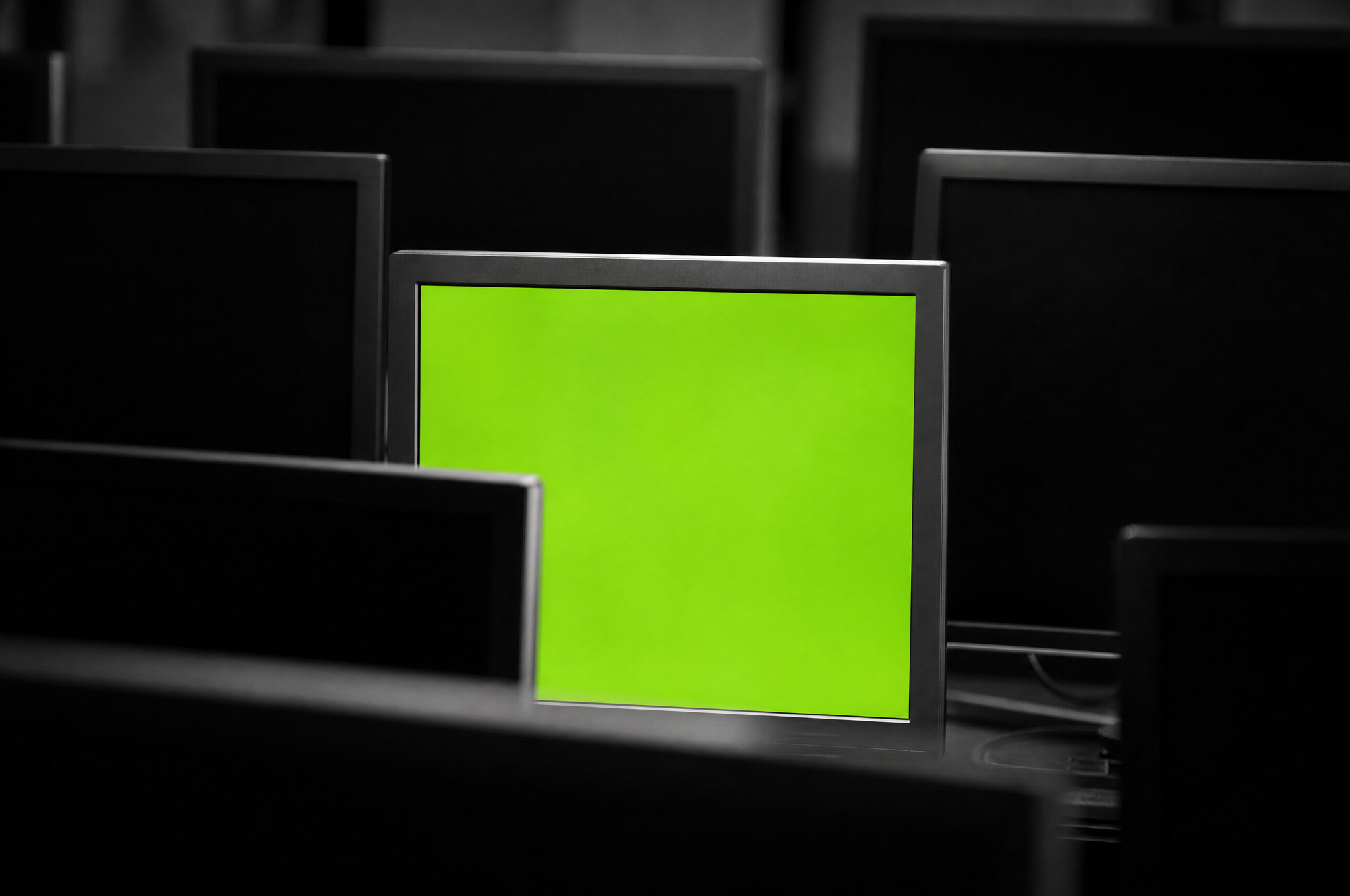 Primo piano su un monitor acceso in verde lime tra schermi spenti