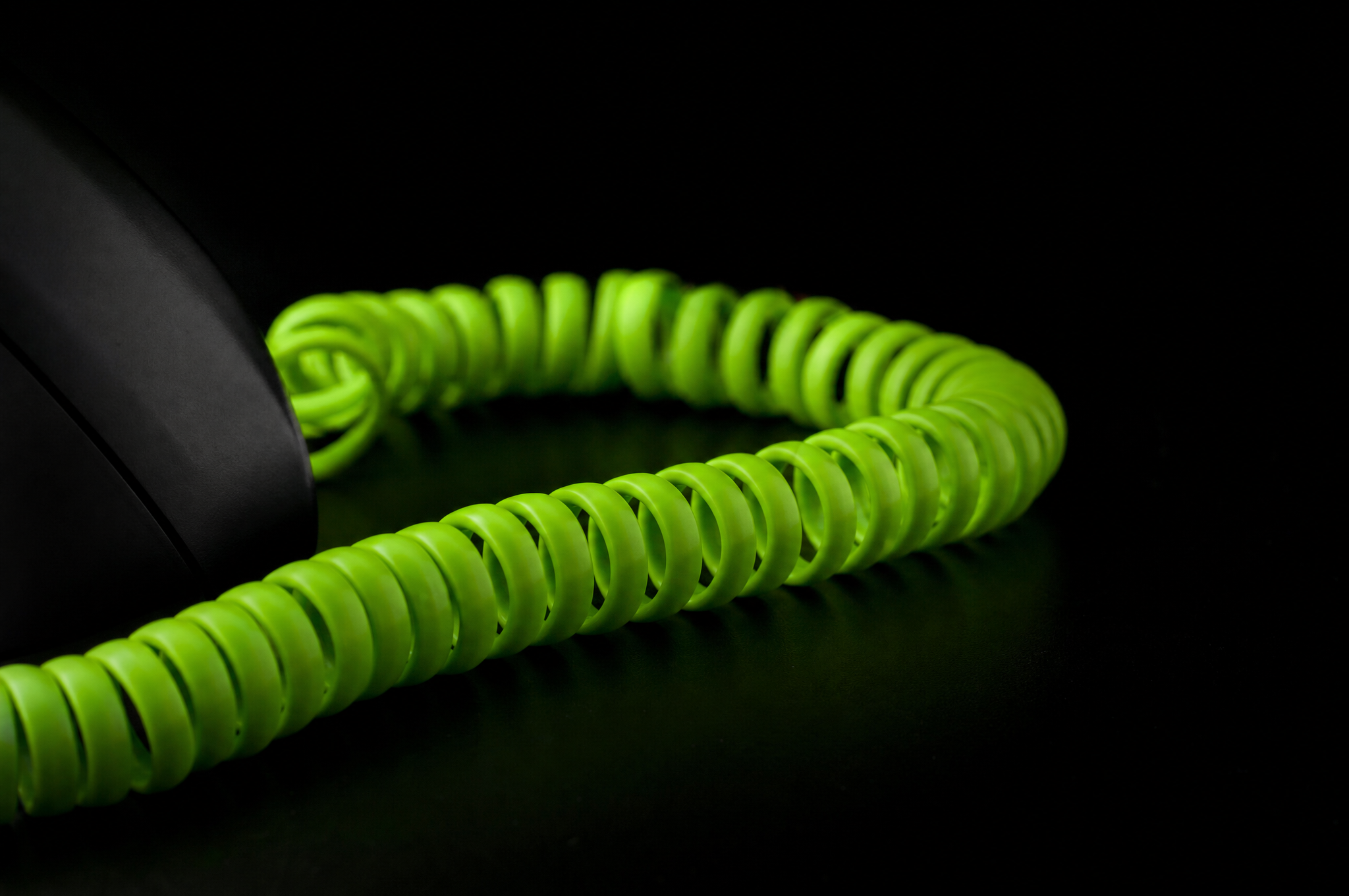 Primo piano sul cavo a spirale del telefono illuminato in verde lime
