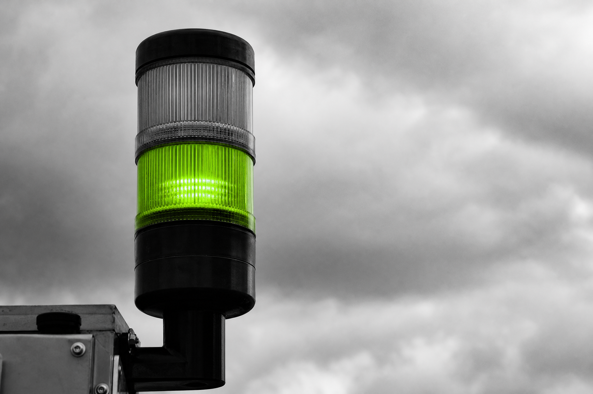 Primo piano sulla luce di una torre di segnale, verde lime contro un cielo coperto